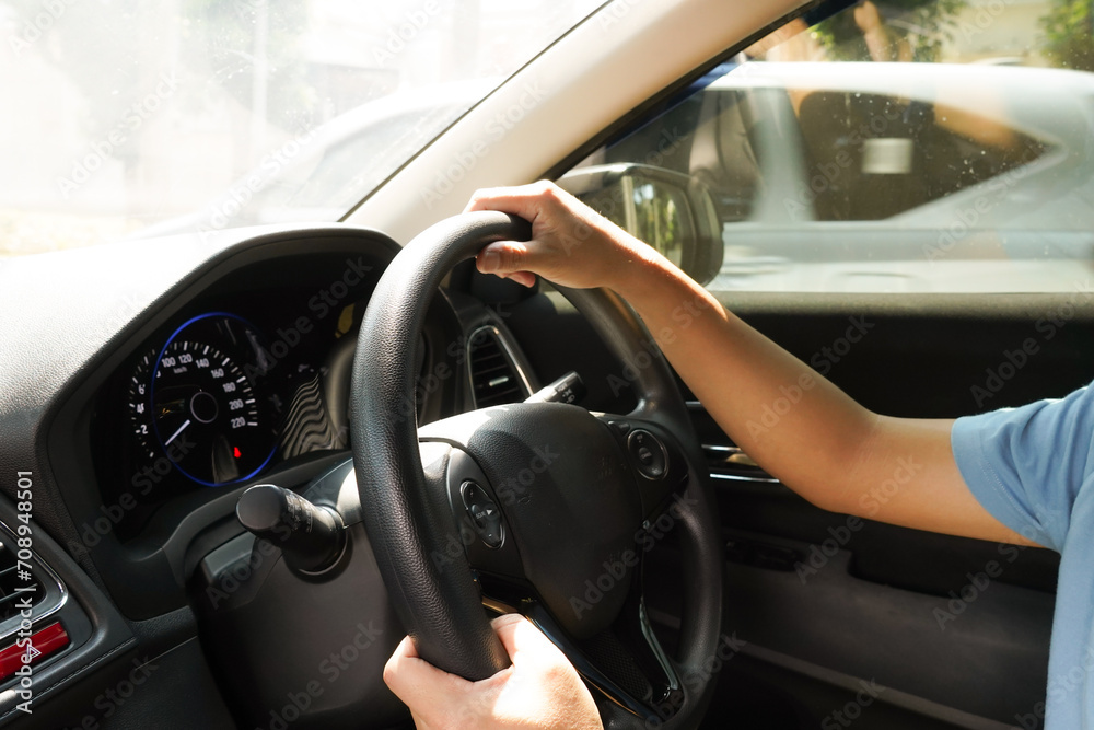 Male hand holding car steering wheel and car dashboard view