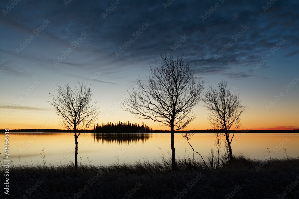 Early autumn morning by a lake with vivid colors of the sky reflecting on the surface of the water Early autumn morning by a lake with vivid colors of the sky reflecting on the surface of the water