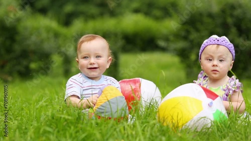 boy and girl sit on fresh green grass with balls of meadow photo