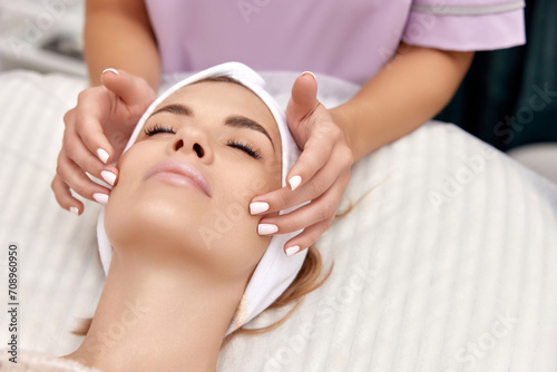 Beautiful woman getting face massage treatment in beauty salon. girl enjoys this procedure.