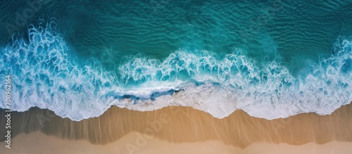 Aerial view of beach with waves washing over wet sand © AkuAku