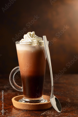 Hot chocolate with whipped cream in a glass mug.
