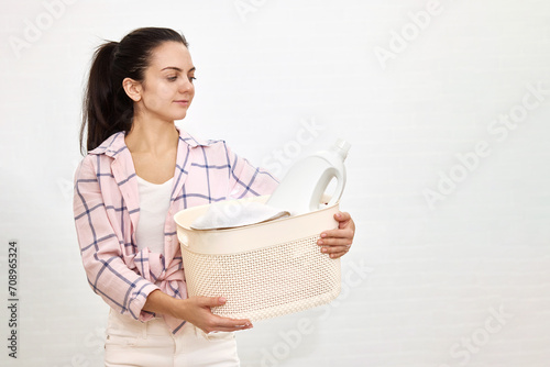 Woman is holding laundry basket with white clothes, copy space, housekeeping