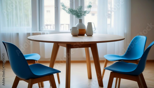 Round wooden dining table and blue chairs. Scandinavian, mid-century home interior design of modern dining room. © AT