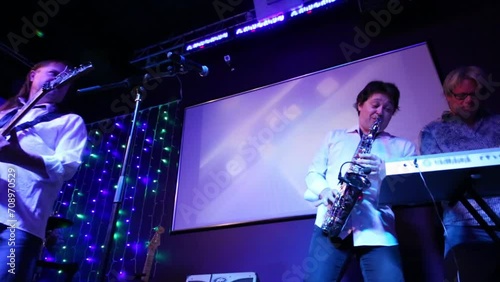 Saxophonist and soloist of band of four men perform in night club photo
