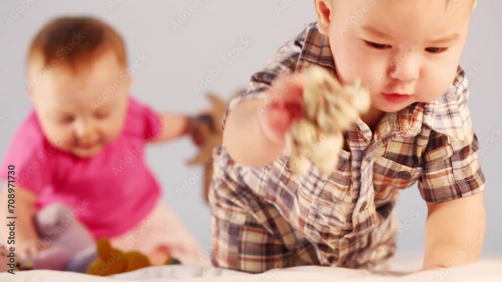 boy crawling towards toy and raises it, behind him plays girl boy crawling towards toy and raises it, behind him plays girl