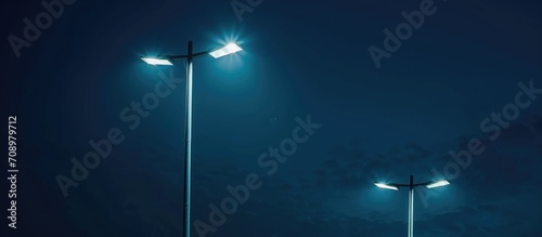 Contemporary urban street lights powered by electricity, shining against the dark night sky.