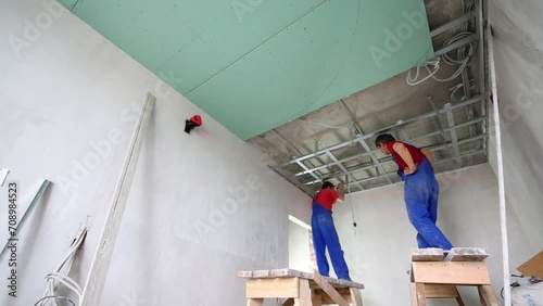 Two workers in uniform install framework for hung ceiling photo