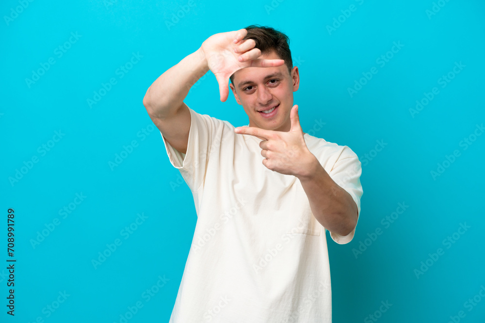 Fototapeta premium Young handsome Brazilian man isolated on blue background focusing face. Framing symbol