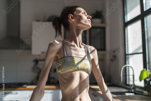 Woman with an eating disorder, anorexia nervosa, in kitchen  photo