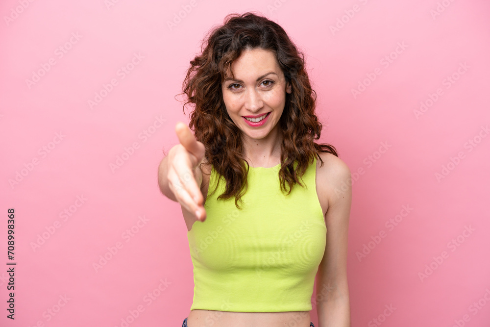Young caucasian woman isolated on pink background shaking hands for closing a good deal Young caucasian woman isolated on pink background shaking hands for closing a good deal