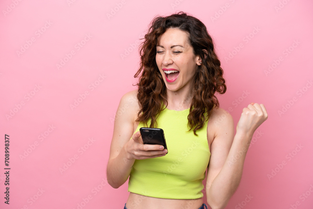 Young caucasian woman isolated on pink background with phone in victory position Young caucasian woman isolated on pink background with phone in victory position