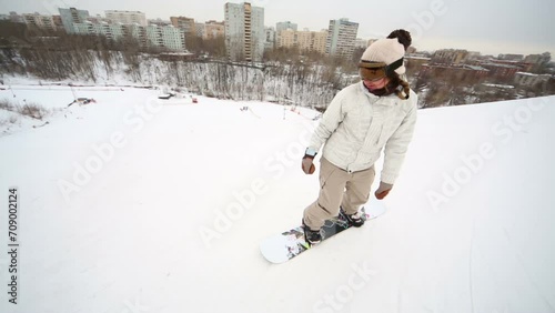 Girl snowboarder coming down the slope near the town photo