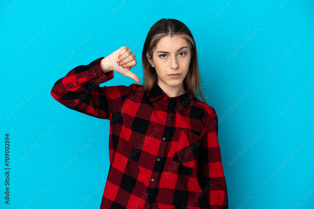Young caucasian woman isolated on blue background showing thumb down with negative expression Young caucasian woman isolated on blue background showing thumb down with negative expression
