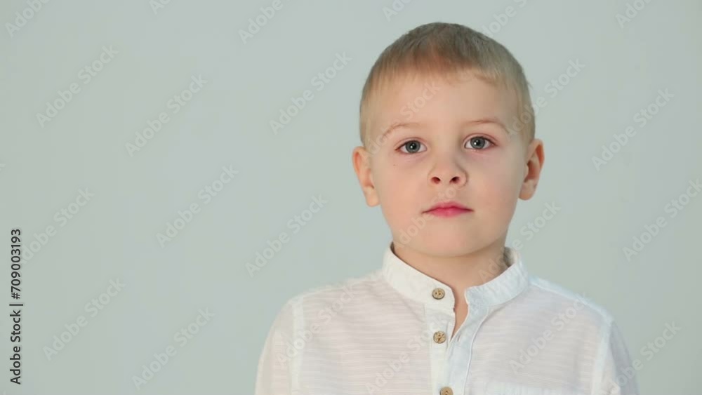 Little boy in a white shirt standing next to a gray wall Little boy in a white shirt standing next to a gray wall