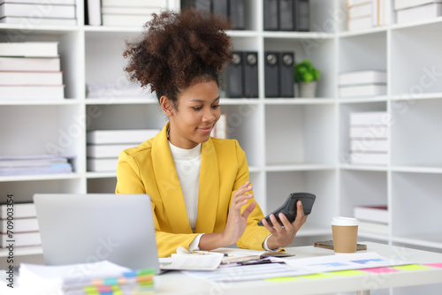 African businesswoman doing paperwork, writing notes and analyzing financial data.