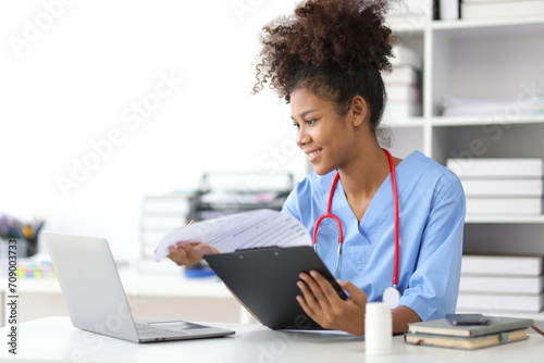 African female doctor in office doing paperwork and writing prescriptions. photo