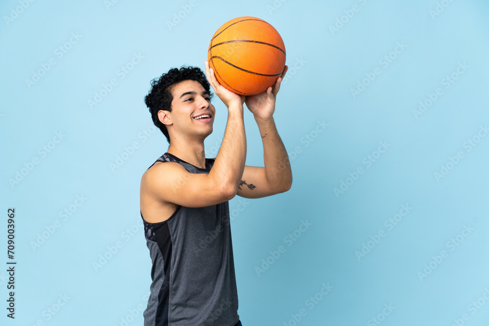 Young Venezuelan man isolated on blue background playing basketball