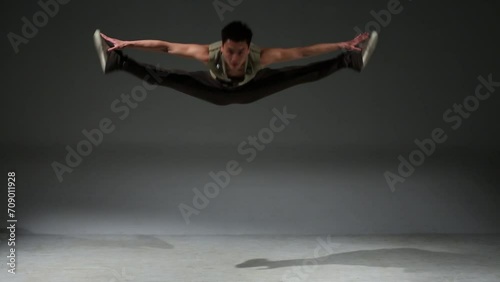 Asian acrobat man in medieval hunting costume jumps in studio photo