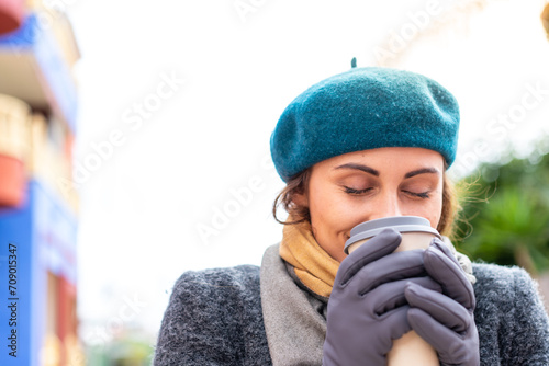 Brunette woman holding a take away coffee at outdoors © luismolinero
