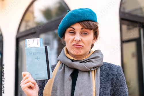 Brunette woman holding a passport at outdoors with sad expression © luismolinero