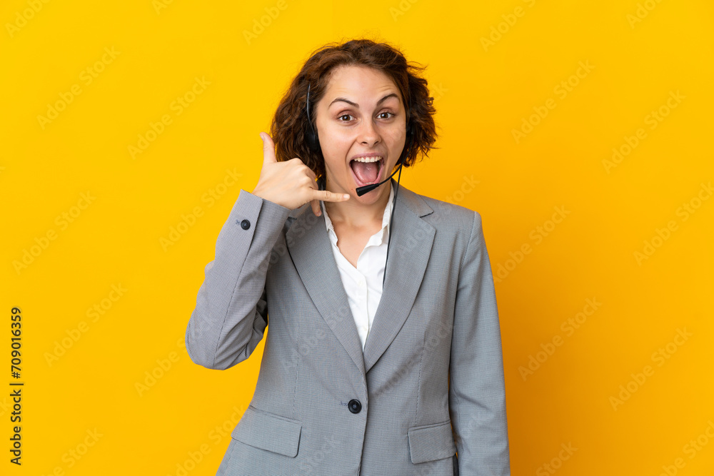 Young English woman isolated on yellow background making phone gesture. Call me back sign Young English woman isolated on yellow background making phone gesture. Call me back sign