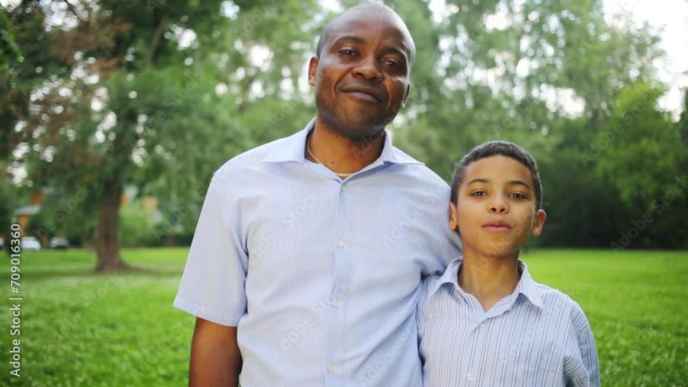 Happy father and son standing embracing in the summer park Happy father and son standing embracing in the summer park