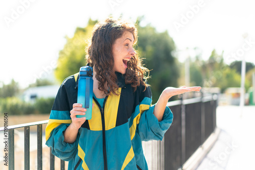 Young sport woman with a sport bottle of water at outdoors with surprise facial expression
