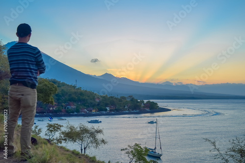 a man watching the sunset on amed beach, bali