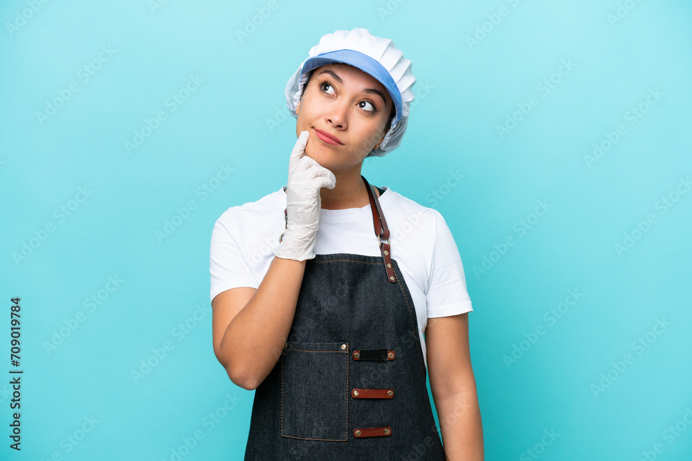 Fishwife Argentinian woman isolated on blue background having doubts while looking up Fishwife Argentinian woman isolated on blue background having doubts while looking up