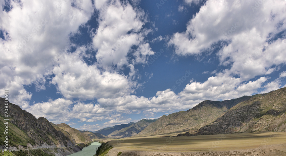 Katun river in mountains under blue sky with clouds