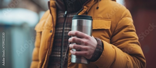 Close-up of man holding a thermos with hot drink, representing a productive day at work with coffee.