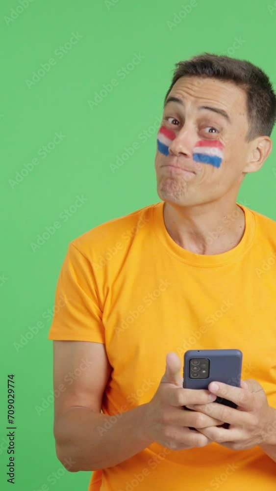 Dutch supporter looking at his mobile smiling and showing it. Dutch supporter looking at his mobile smiling and showing it.