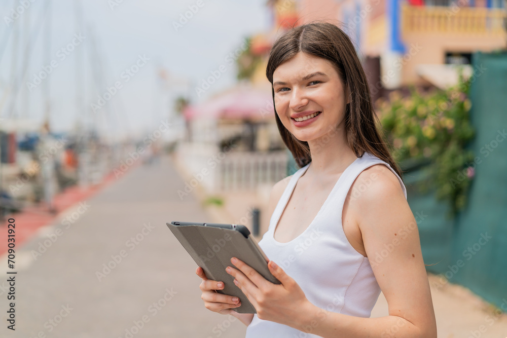 Young pretty woman at outdoors holding a tablet with happy expression Young pretty woman at outdoors holding a tablet with happy expression