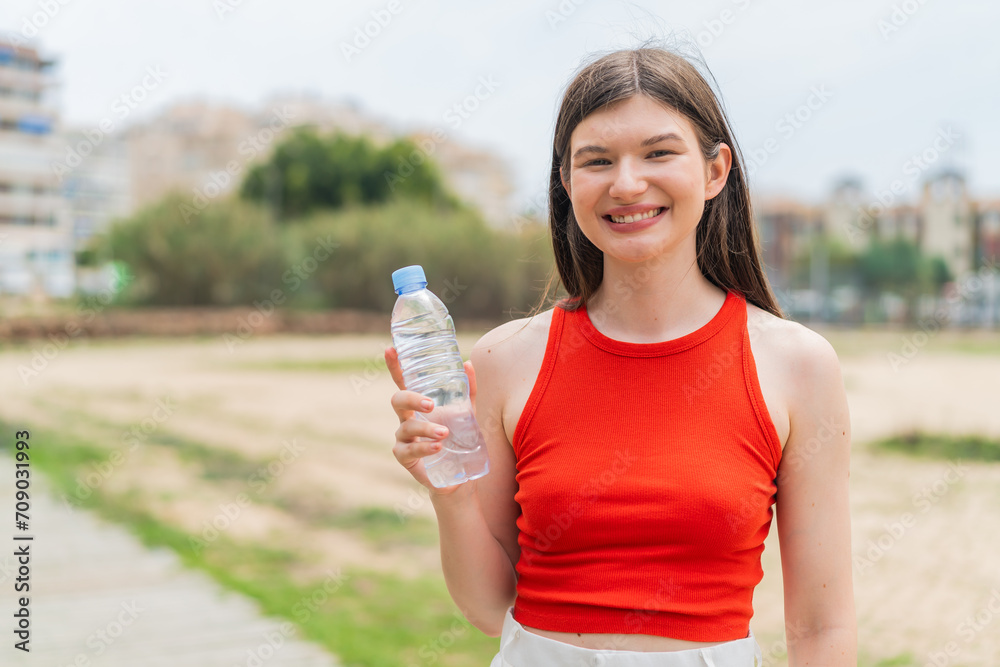 Young pretty Ukrainian woman with a bottle of water at outdoors smiling a lot Young pretty Ukrainian woman with a bottle of water at outdoors smiling a lot