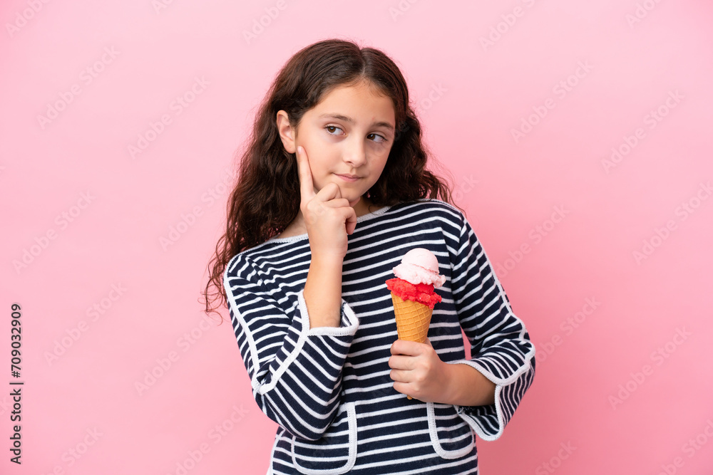 Little caucasian girl holding an ice cream isolated on pink background thinking an idea while looking up Little caucasian girl holding an ice cream isolated on pink background thinking an idea while looking up