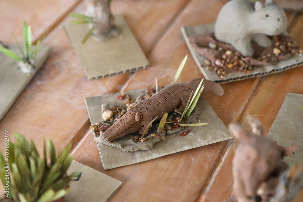 Obraz premium Clay crocodile sculpture made by children in ceramics class. Ceramic animal crafts made by hand in art class for children.