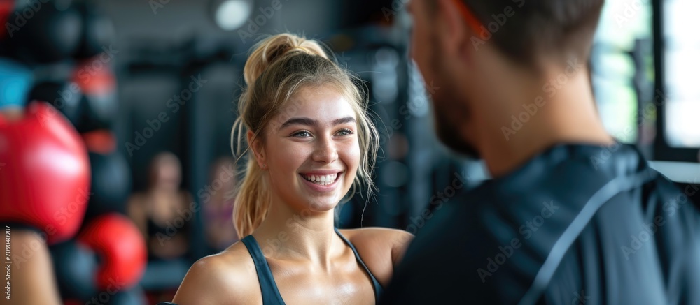 Obraz premium Smiling female kickboxer training with instructor at gym