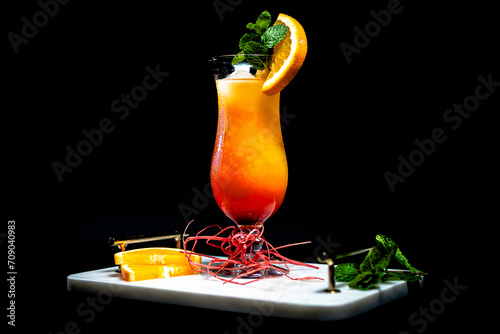 Tequila sunrise on a black background, on a marble tray © Joanna