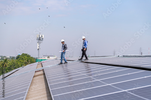 Engineers walking on roof inspect and check solar cell panel by hold equipment box and radio communication ,solar cell is smart grid ecology energy sunlight alternative power factory concept 