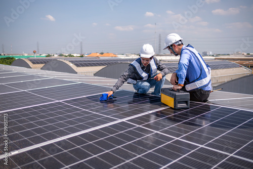 Engineers walking on roof inspect and check solar cell panel by hold equipment box and radio communication ,solar cell is smart grid ecology energy sunlight alternative power factory concept 