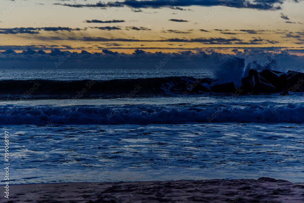 sunset over the wavy sea with an orange sky and clouds