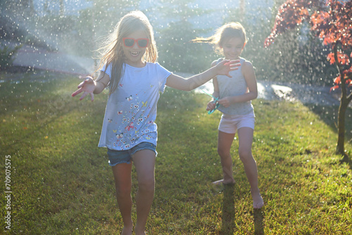 Child playing with garden sprinkler. Kids run and jump. Summer outdoor water fun in the backyard. Child playing with garden sprinkler. Kids run and jump. Summer outdoor water fun in the backyard