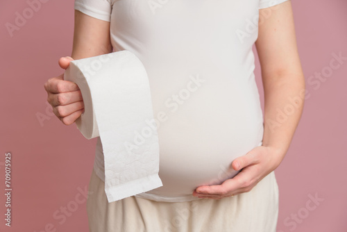 Bild auf Leinwand Pregnant woman holding toilet paper, studio pink background