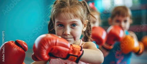 Preschool children are practicing in the gym with gloves for boxing.