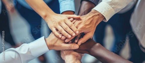 Diverse office workers joining hands symbolize strong productive teamwork. Cooperation and unity among business employees.