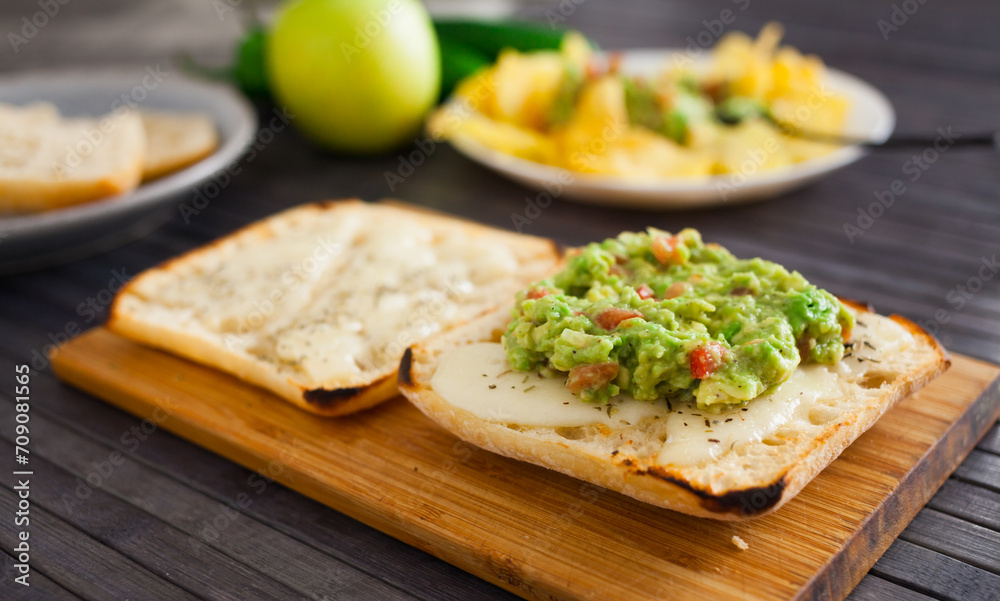 Toasted slices of square bread with warm cheese and homemade guacamole on plate for healthy breakfast
