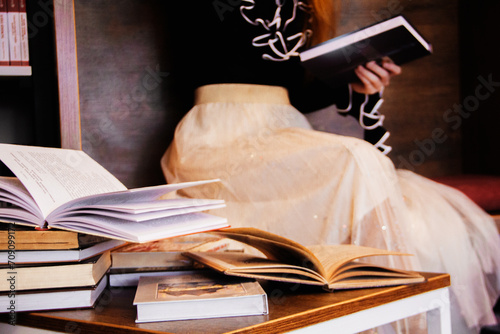 A lonely red-haired girl student in a black blouse with ruffles and a light white skirt holds in her hands a closed book in a dark binding in a quiet cozy place photo