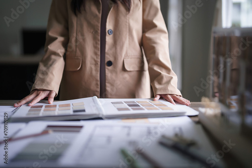 Female architect choosing color swatch sample to design interior of building project on blueprint photo