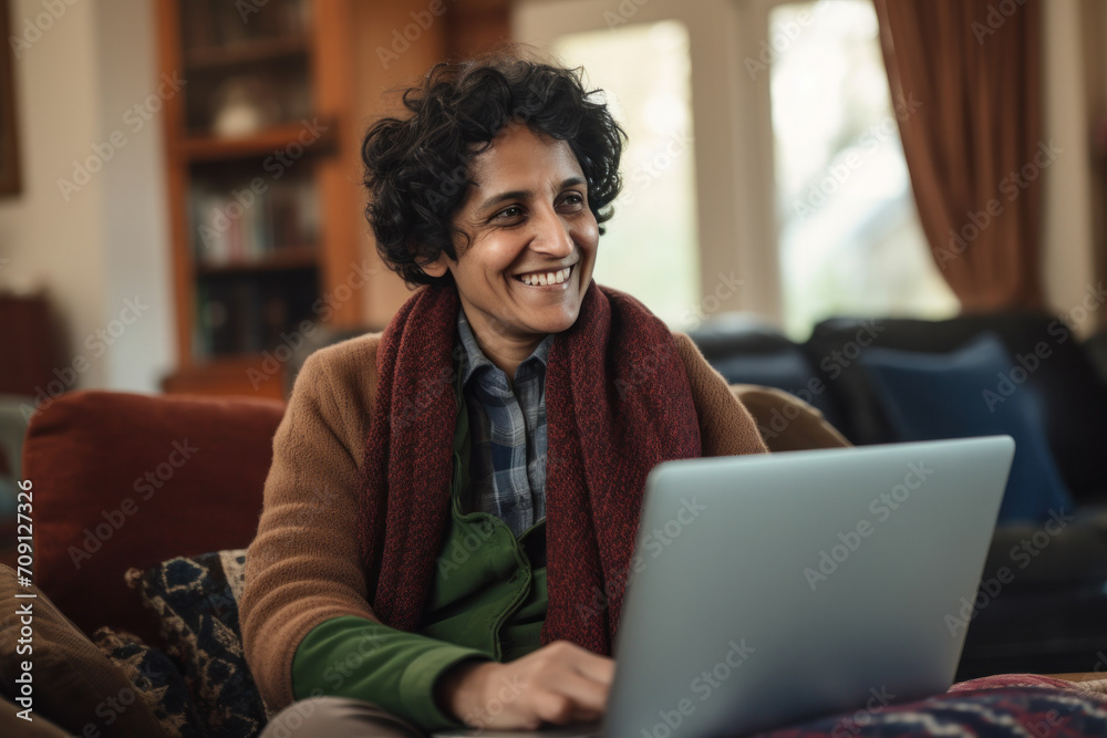 Cheerful, mature Indian woman at home, contentedly using a laptop with confidence and joy. Cheerful, mature Indian woman at home, contentedly using a laptop with confidence and joy.